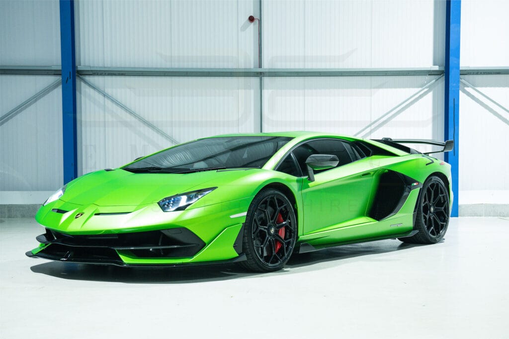 Bright green lamborghini aventador parked in a clean, white industrial garage, showcasing its sleek design and black accents.