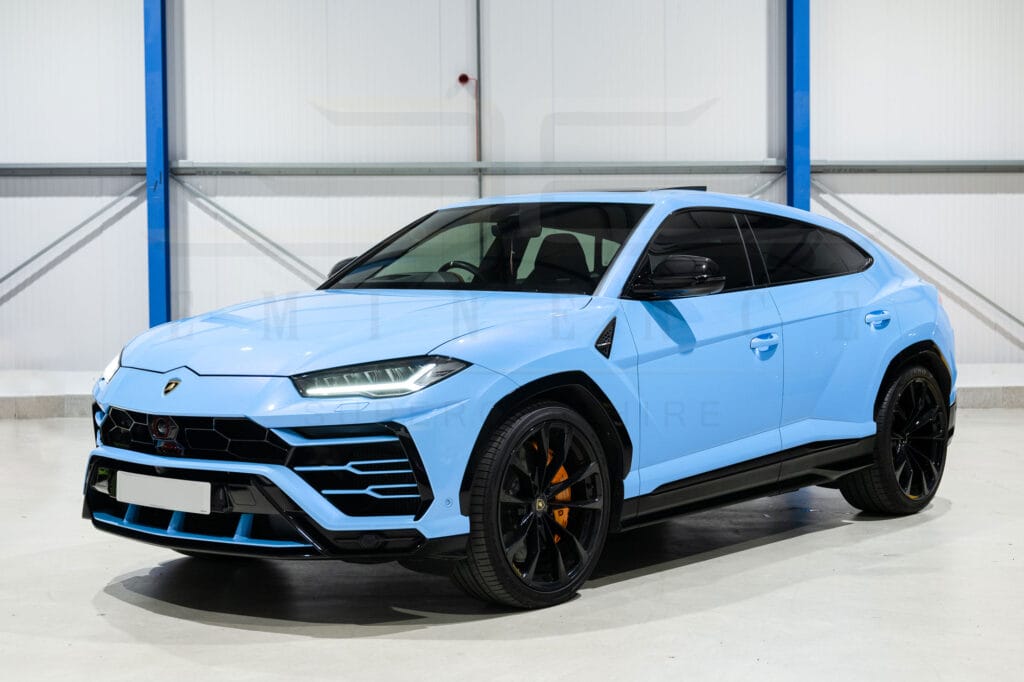 Blue lamborghini urus suv parked in an indoor facility, showcasing its sleek design and sporty stance.