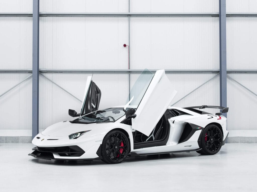 White lamborghini sports car with doors open, parked inside a modern garage.
