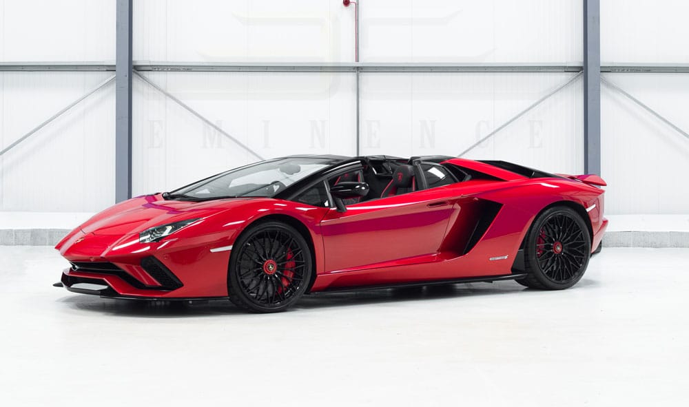 A red lamborghini aventador with doors open, parked inside a modern showroom featuring a white background.