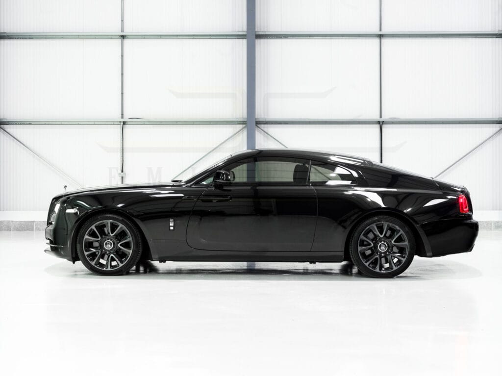 Black luxury sedan parked indoors, side view, with a clean white background.
