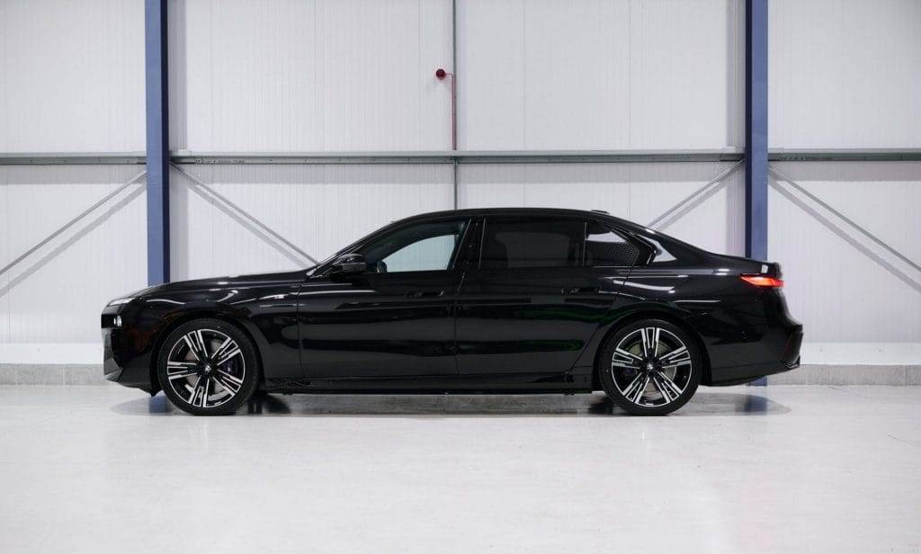 A black sedan available for hire, parked indoors against a white background, side view.