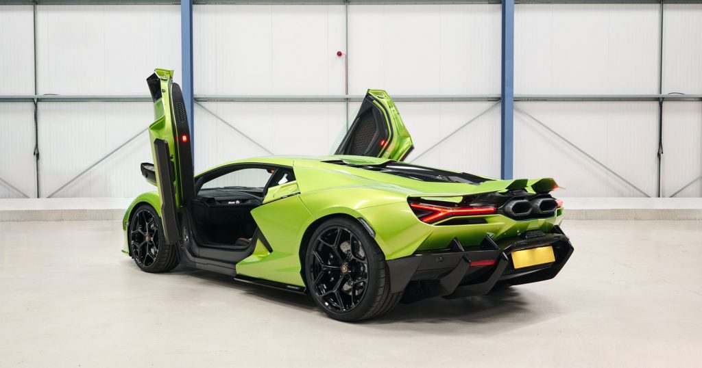 A bright green sports car with gullwing doors open, showcasing its sleek design and black wheels, available for hire, parked indoors against a white and metal background.